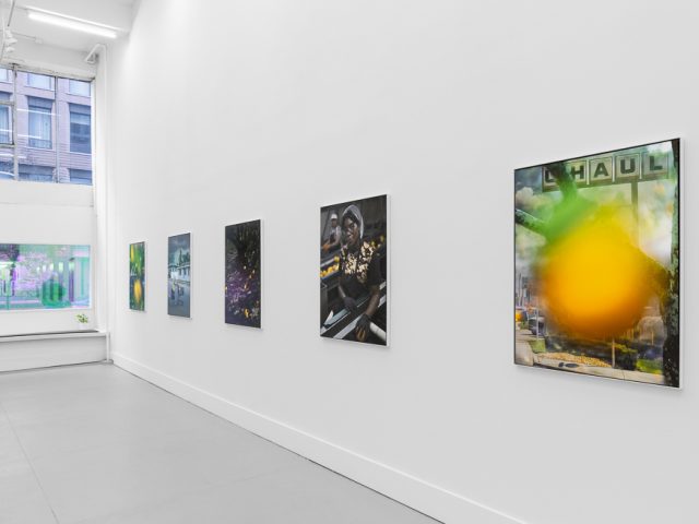 A modern art gallery displays a vintage orange advertisement alongside other artworks, possibly with a Florida theme.