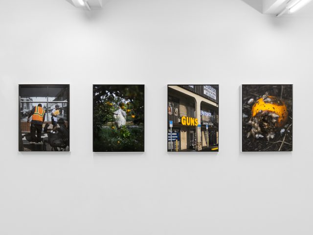 A modern art gallery displays a vintage orange advertisement alongside other artworks, possibly with a Florida theme.