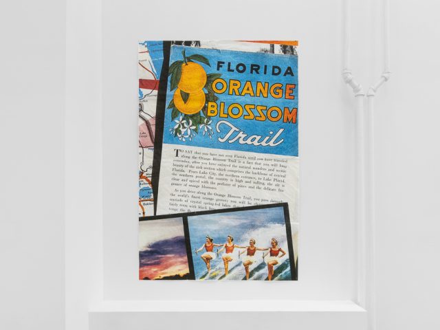 A modern art gallery displays a vintage orange advertisement alongside other artworks, possibly with a Florida theme.