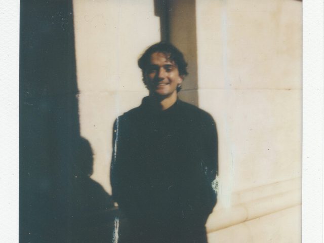 Click for sizes / editions / prices. A polaroid of a young man in a black sweatshirt with dark hair smiling.