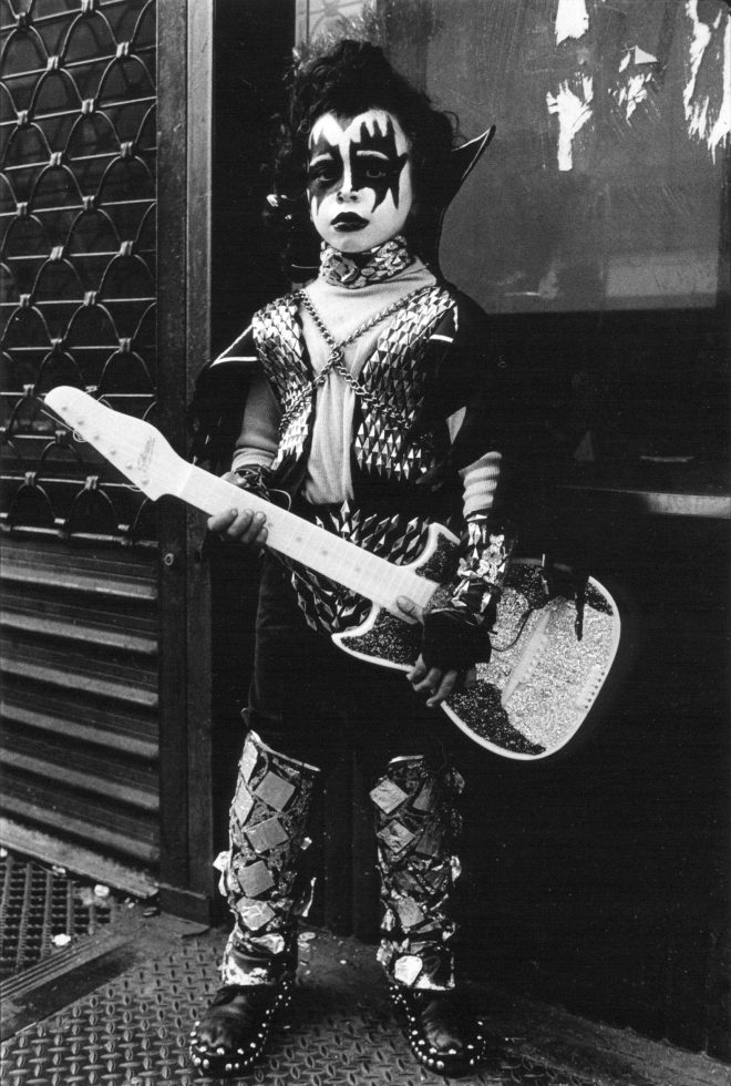 A black and white photograph of a child dressed as KISS.