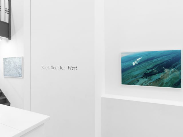 An installation image of a contemporary photography exhibition in a white-walled gallery.