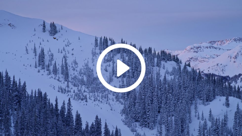 An image of snowy rocky mountains at dusk.