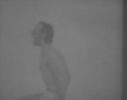 A blurry black and white image of a young man seated in profile with his hands by his sides.