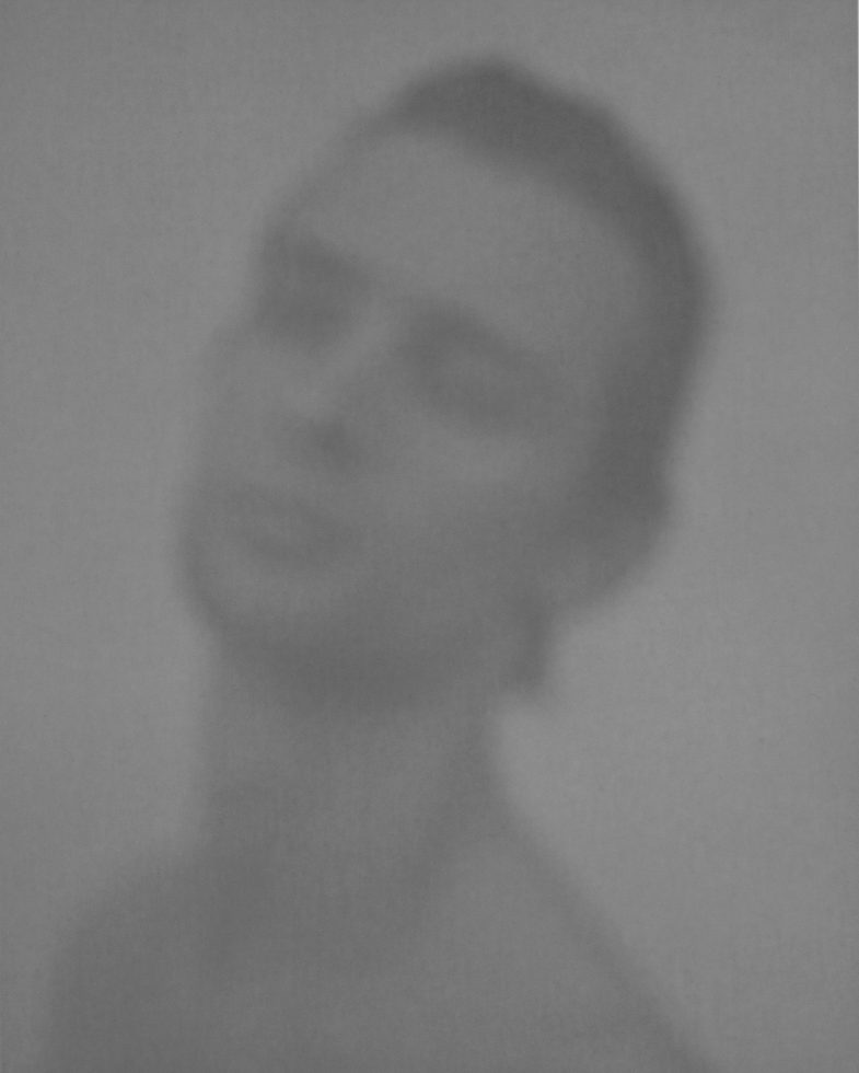 A blurry black and white image of a young man's face.