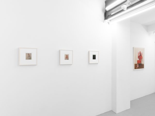 Small color photographs displayed on stark white gallery walls.