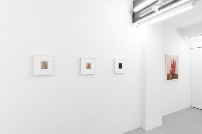 Small color photographs displayed on stark white gallery walls.
