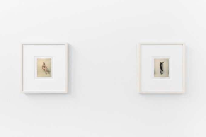 Small color photographs displayed on stark white gallery walls.