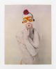 Figure covered in white with a vibrant floral mask (orange eyes, pink mouth, red accents) against a plain backdrop.