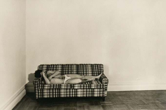 A black and white photograph of a man in white underwear lying on a sofa.