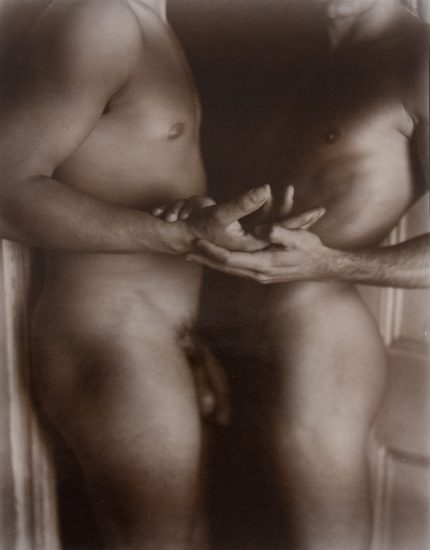 A black and white photograph of two nude people embracing