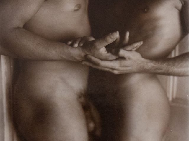 A black and white photograph of two nude people embracing