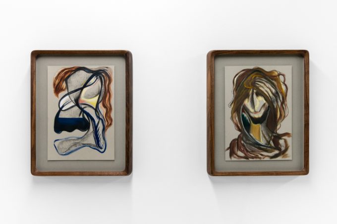 A series of abstract framed drawings hang on a white gallery wall under a black and white artist name and exhibition title.