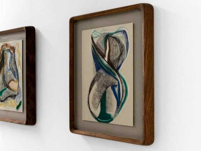 A series of abstract framed drawings hang on a white gallery wall under a black and white artist name and exhibition title.