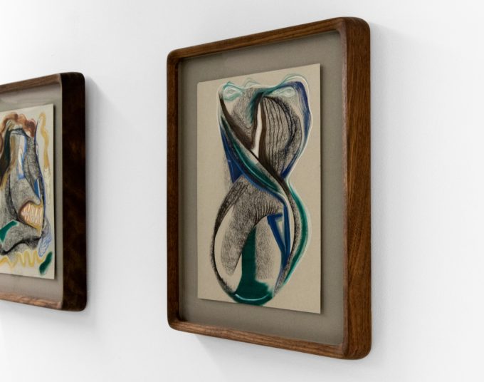 A series of abstract framed drawings hang on a white gallery wall under a black and white artist name and exhibition title.