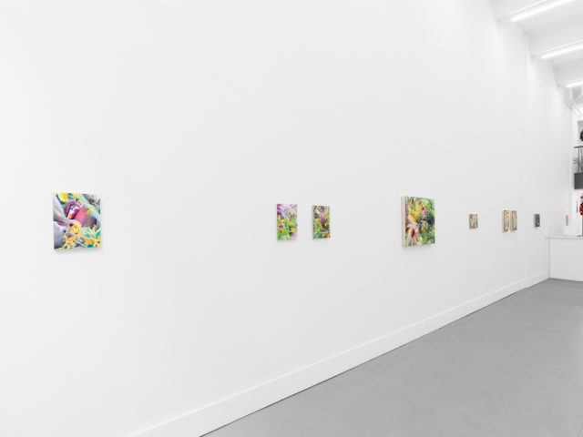 Colorful artworks on a bright white gallery wall in neutral lighting.