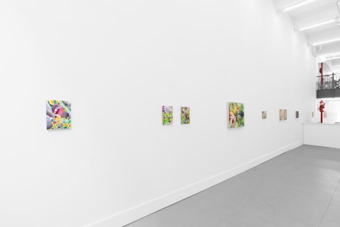Colorful artworks on a bright white gallery wall in neutral lighting.