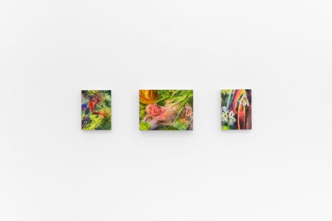 Three colorful paintings depict figures and flowers in lush, dreamlike environments with saturated greens, yellows, and reds on a white wall.
