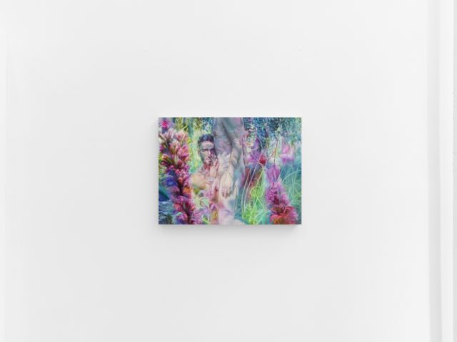 A vibrant painting shows a semi-nude figure among lush, surreal plants in shades of pink, green, and purple on a white gallery wall.