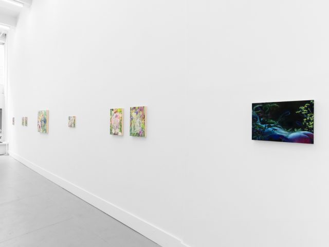 Colorful artworks on a bright white gallery wall in neutral lighting.