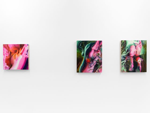 Colorful artworks on a bright white gallery wall in neutral lighting.