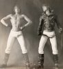 A black and white photograph of two men in white tights, one in a leather jacket.