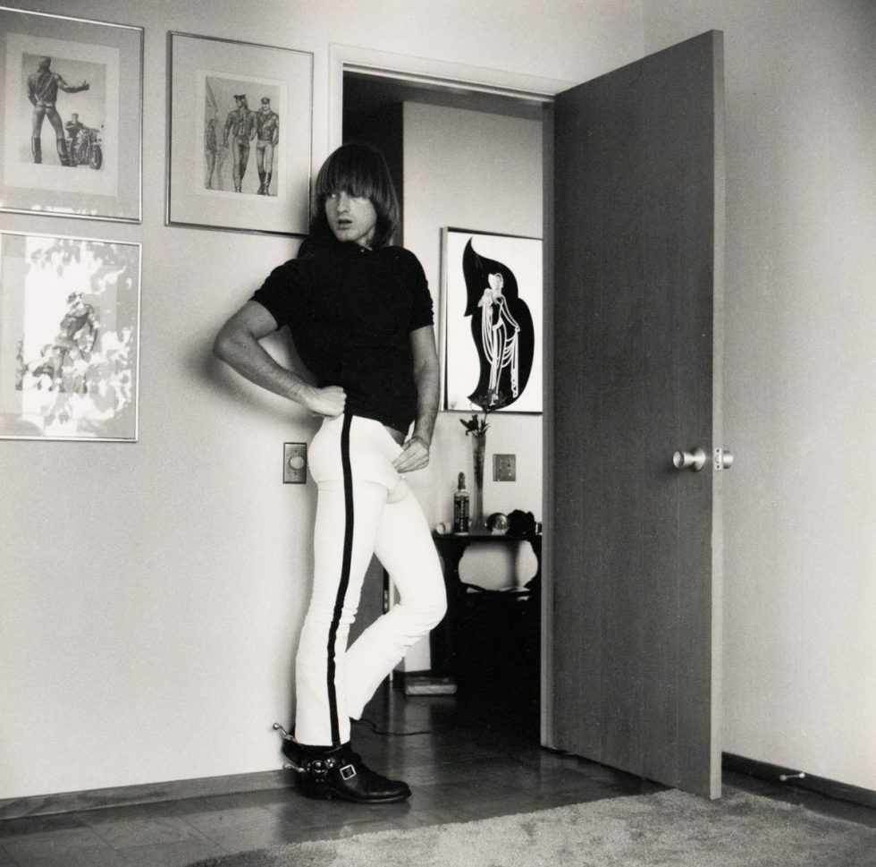 Person posing confidently in a room decorated with bold artwork and fashion illustrations.