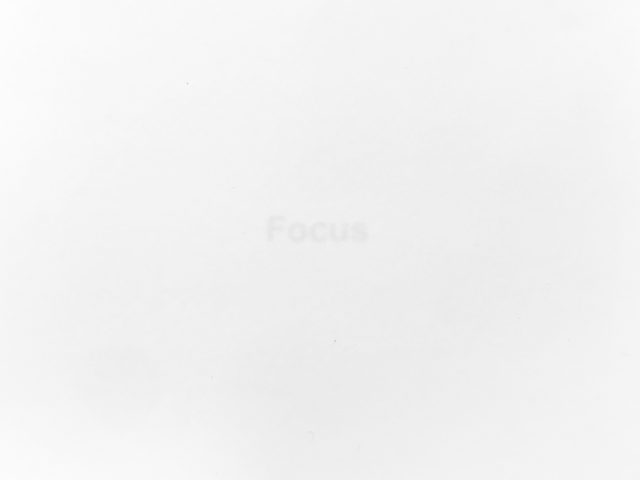 A stark white image features the faint, barely visible word "Focus" in the center, hinting at a minimalist conceptual piece.