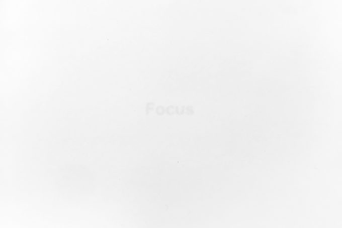 A stark white image features the faint, barely visible word "Focus" in the center, hinting at a minimalist conceptual piece.