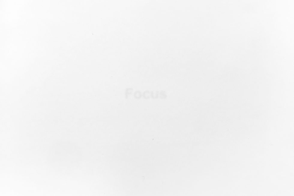 A stark white image features the faint, barely visible word "Focus" in the center, hinting at a minimalist conceptual piece.