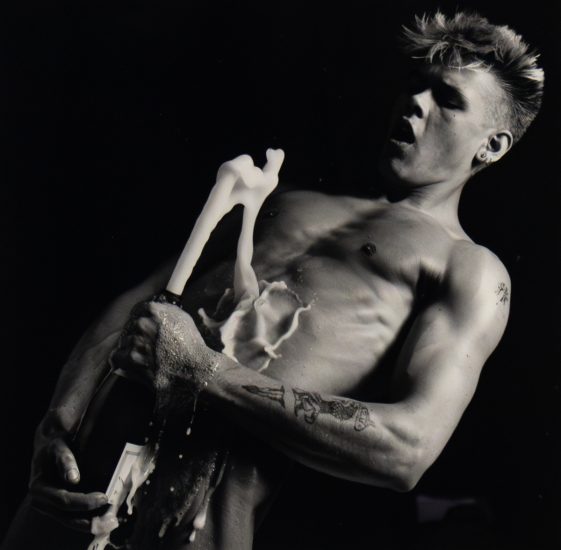 Click for sizes / editions / prices. Shirtless person opens champagne bottle mid-spray, liquid erupts upward as they react with wide eyes and parted lips.