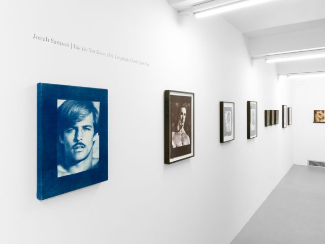 Contemporary artworks displayed along stark white bright gallery walls.