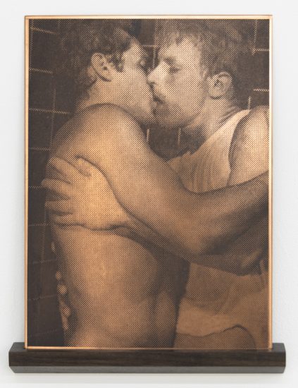 This framed artwork on a dark wooden shelf depicts two individuals embracing in a kiss, rendered in a distinctive halftone pattern.