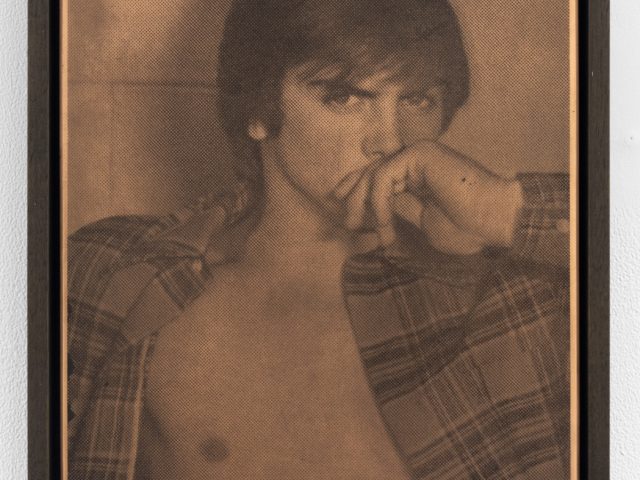 Sepia-toned halftone print of a shirtless person in an open plaid shirt, gazing intensely with hand covering their mouth