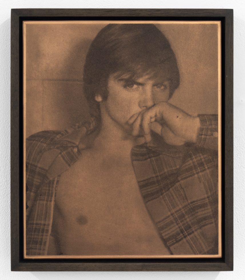Sepia-toned halftone print of a shirtless person in an open plaid shirt, gazing intensely with hand covering their mouth