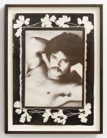 This framed artwork presents a black and white portrait of a man with an afro and mustache, surrounded by a border of white botanical silhouettes.