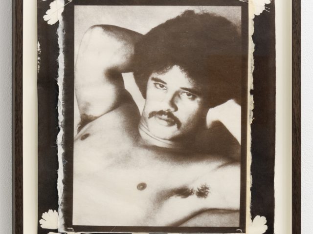 This framed artwork presents a black and white portrait of a man with an afro and mustache, surrounded by a border of white botanical silhouettes.