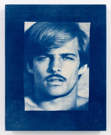 Blue-toned portrait of a shirtless man with parted hair and a mustache, printed on textured canvas with a photographic, vintage appearance.