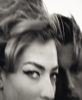 A black and white close-up shot shows a woman's face in the foreground with another person's blurred face behind her.