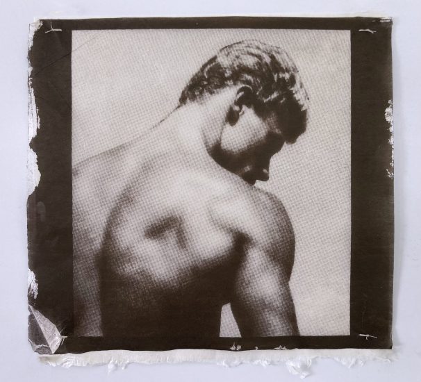 A sepia-toned print shows a shirtless man from behind, looking down and to the side, highlighting his muscular back.