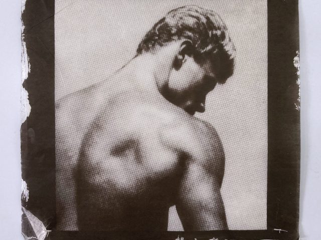 A sepia-toned print shows a shirtless man from behind, looking down and to the side, highlighting his muscular back.