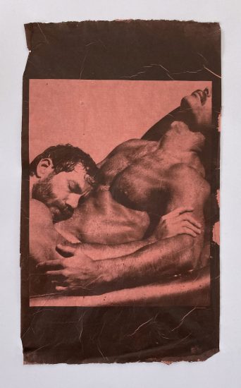 An rose-colored image depicting two men in an intimate embrace.