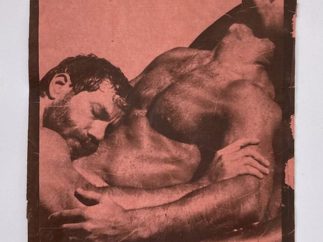 An rose-colored image depicting two men in an intimate embrace.