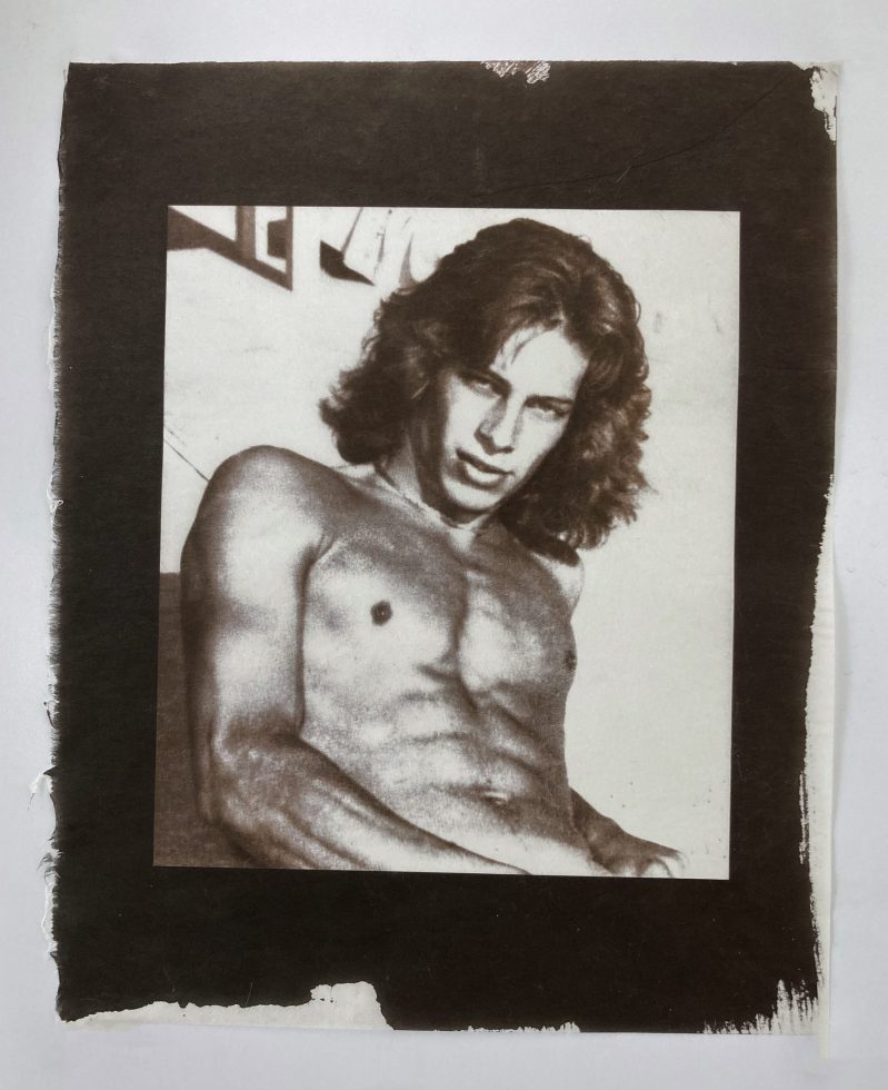 A gold-toned monochromatic portrait shows a shirtless man with wavy hair, looking directly at the viewer with an intense gaze.