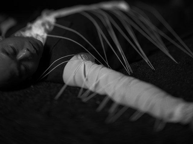A black and white photograph of a person lying on their back.
