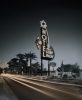A photograph of a motel sign at night with the lights of a car rushing by.