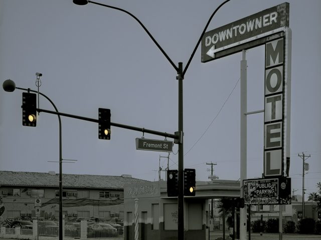 A photograph of a streetlight with a motel sign behind it.