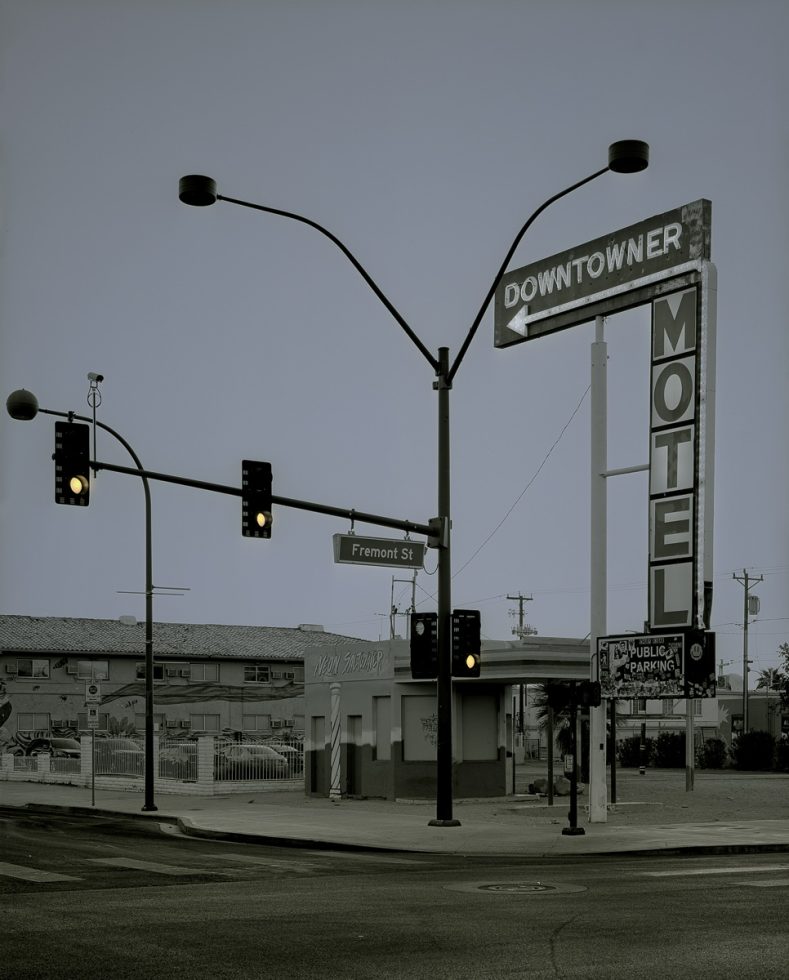 A photograph of a streetlight with a motel sign behind it.