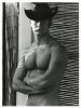 A black and white photograph of a shirtless man in a black cowboy hat.