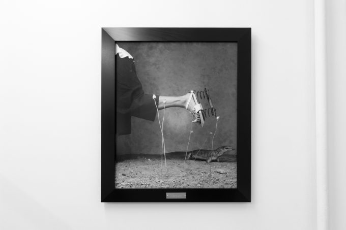 A photograph of black and white photographs in black frames hanging in a contemporary gallery setting.